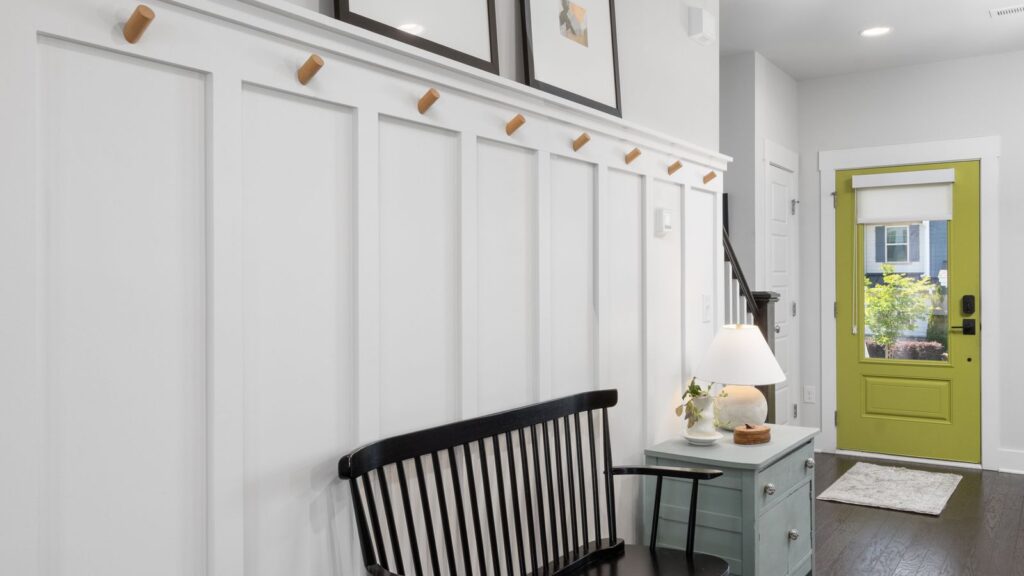 Stylish entryway featuring a green door, black bench, and decorative elements.