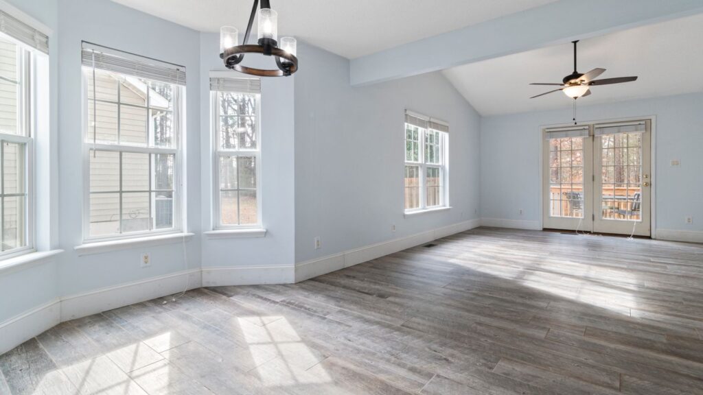Bright empty living room with wooden floor and ceiling fan, ideal for interior design use.