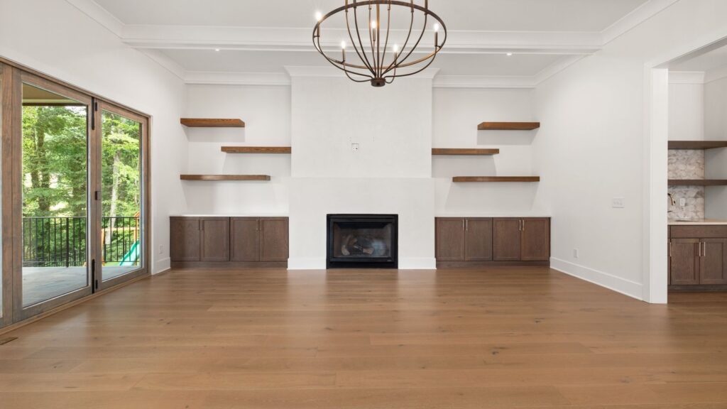 Spacious living room with wooden floors, chandelier, and fireplace.