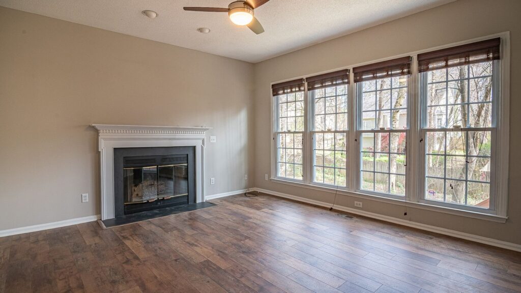 A bright and spacious modern living room interior with a fireplace and large windows.