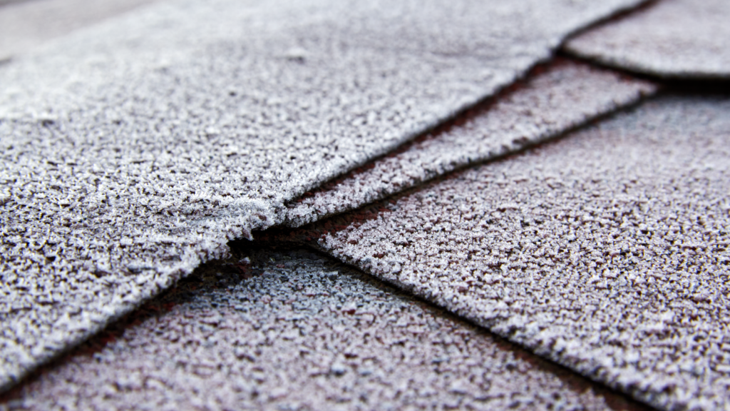 Close-up view of frost-covered roof shingles showcasing texture and cold weather effects.