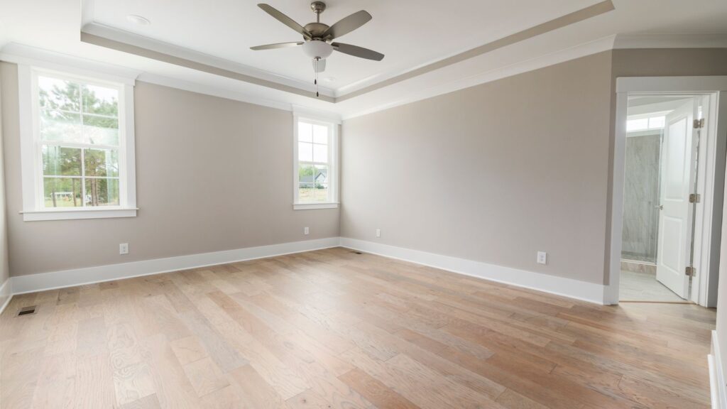 Open, modern bedroom with wooden floors and ceiling fan, ideal for staging.