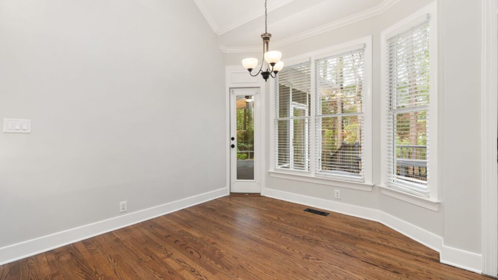 Spacious empty room with wooden floors and large windows offering ample light.